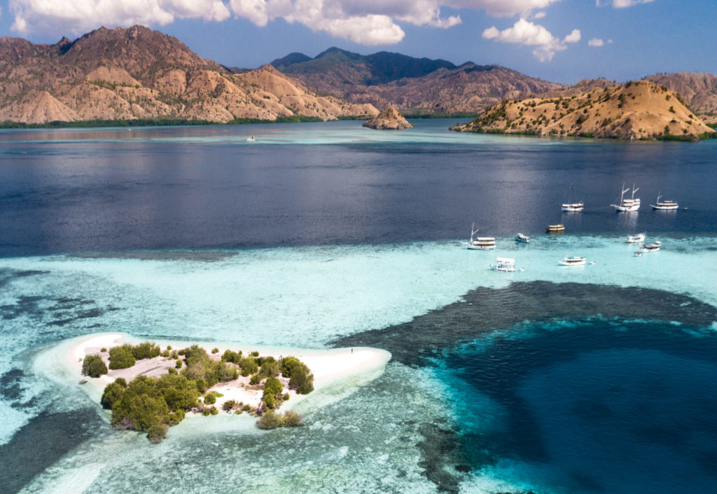 White and pink sand beach encircled by crystal blue water and magnificent reef | Hello Flores