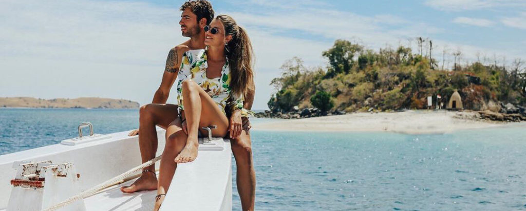 A couple is sitting on the bow of a boat