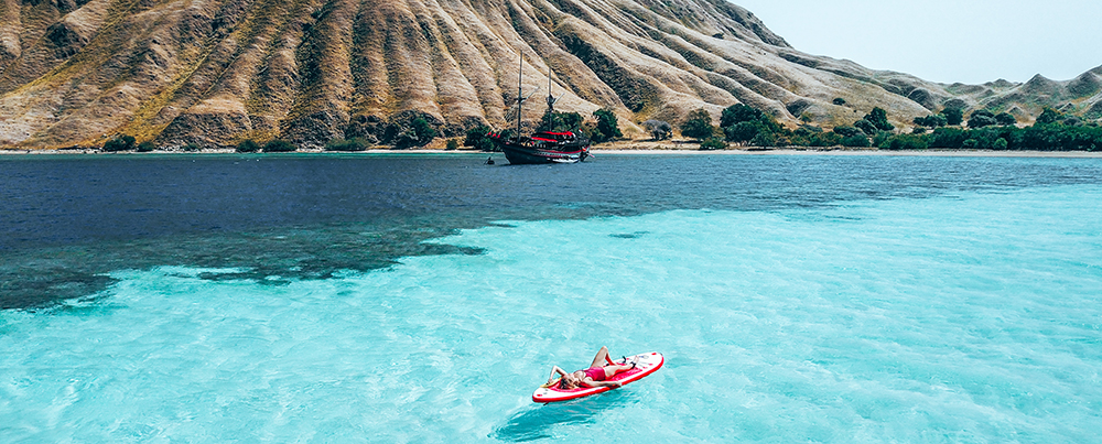 A woman is lying on a kayak on the Komodo sea